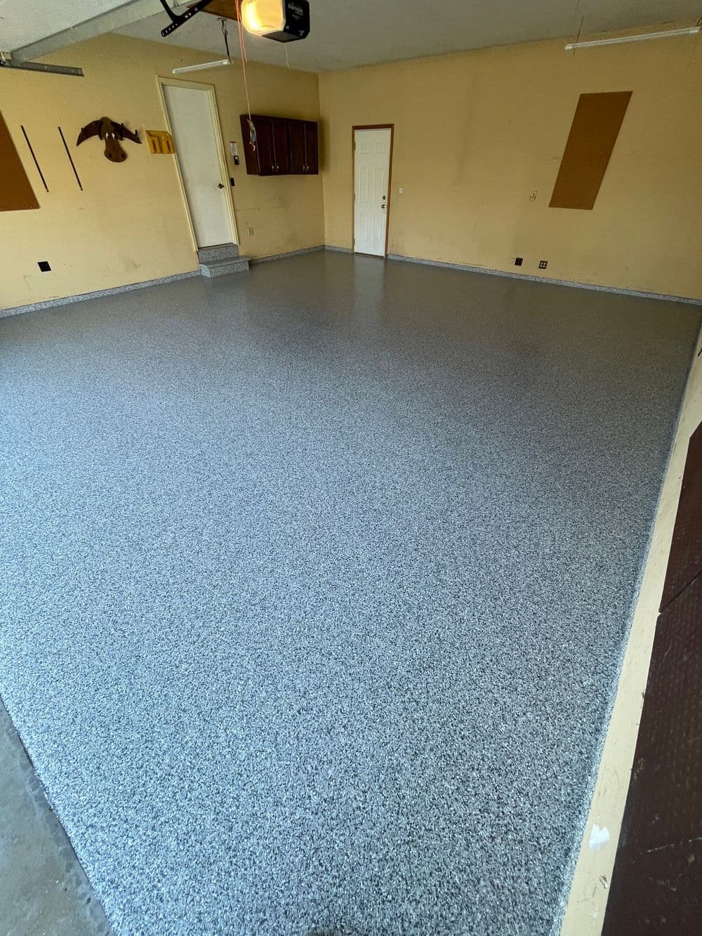 Newly coated gray epoxy garage floor with speckled texture and clean walls.