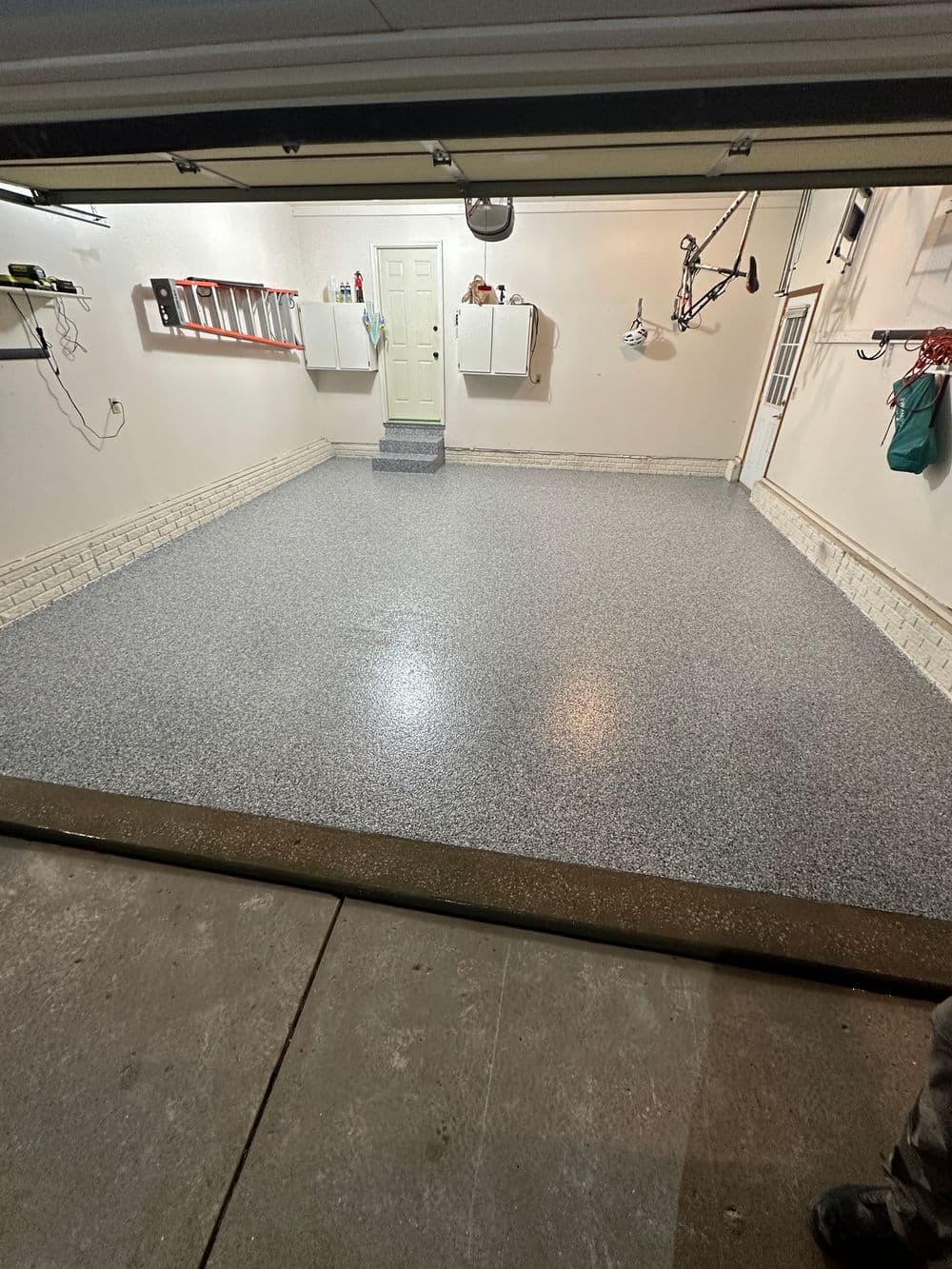Clean and organized garage interior with speckled flooring and storage cabinets.