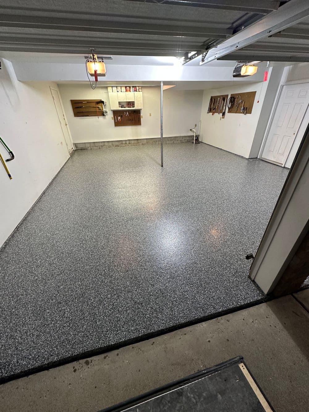 Clean, spacious garage with polished gray epoxy floor and wall-mounted storage shelves.
