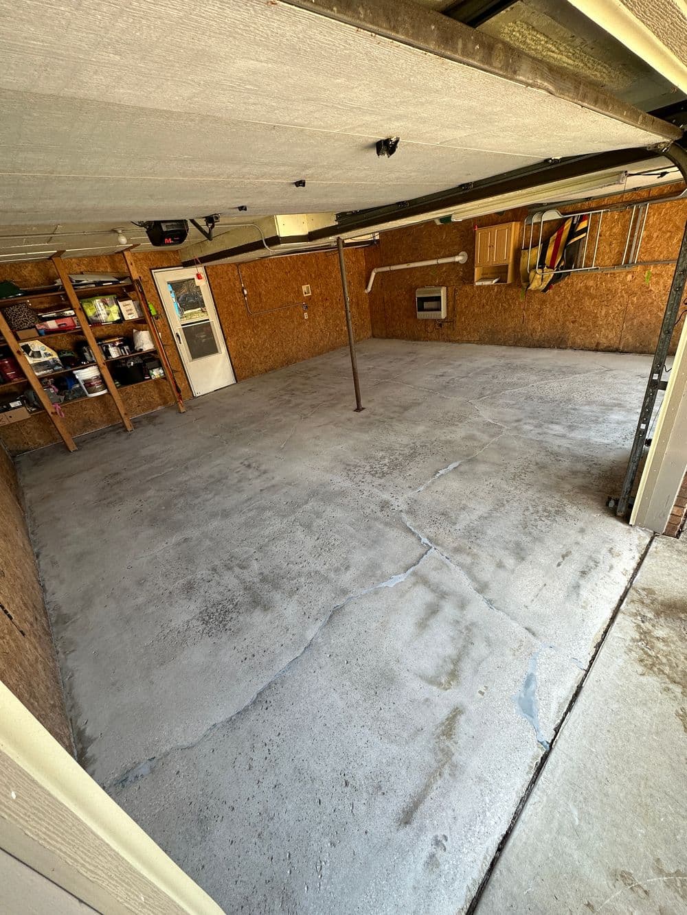 Clean, empty garage with concrete floor and organized shelves against the walls.