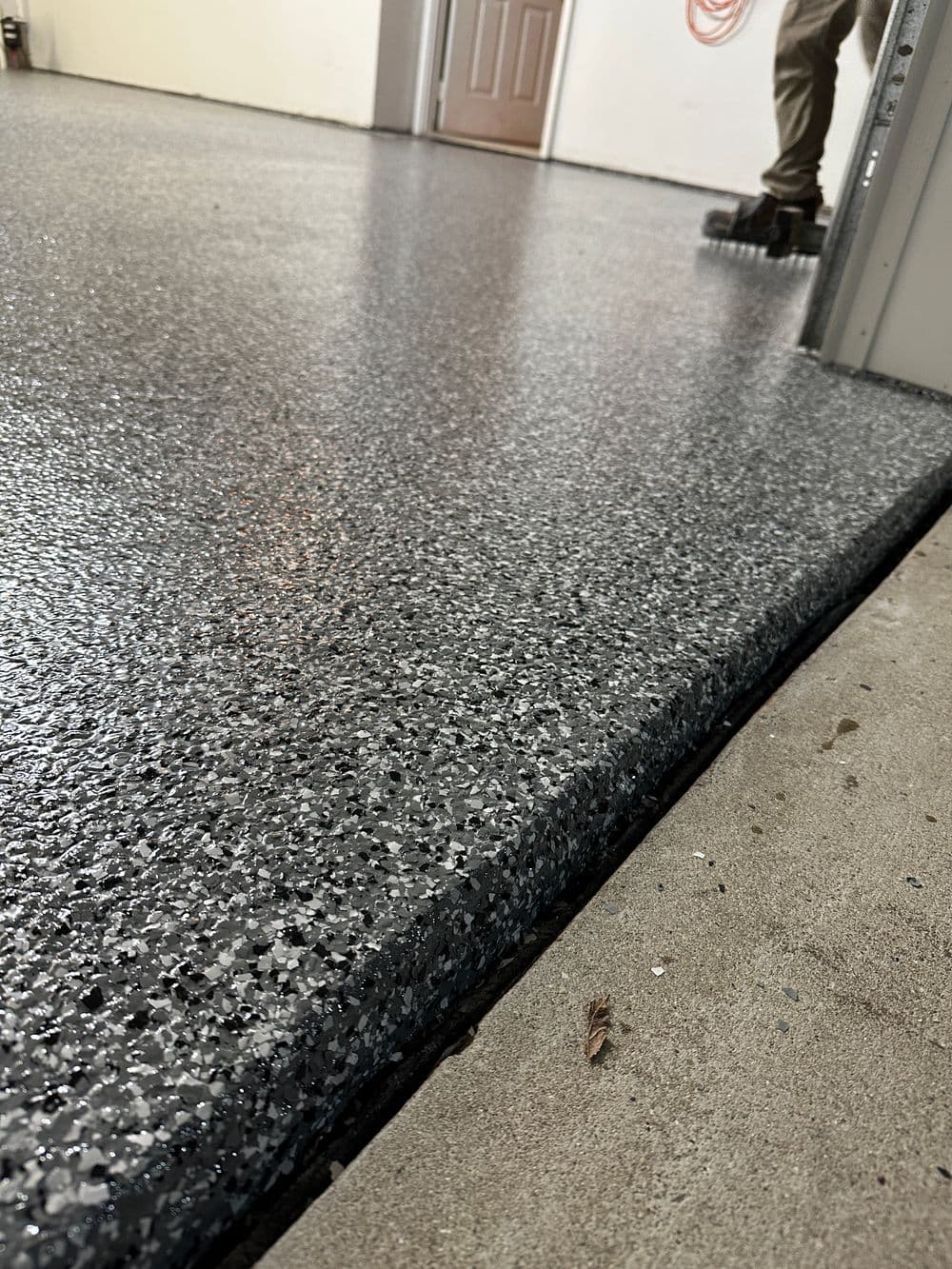 Epoxy garage floor coating with textured finish and smooth transition to concrete edge.