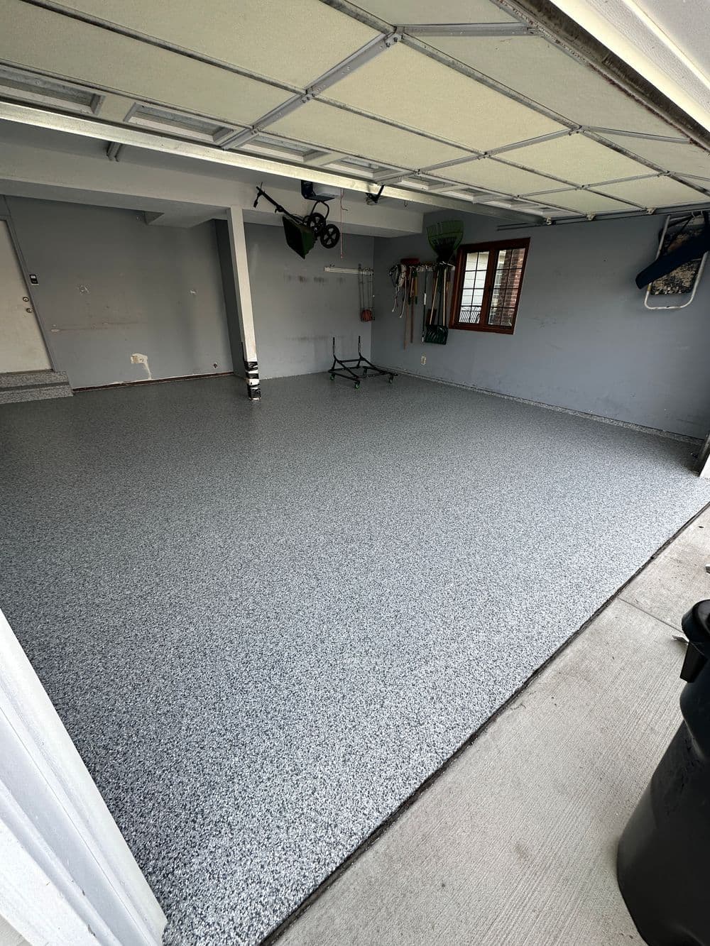 Clean garage interior with gray flake epoxy flooring and organized tools on the wall.