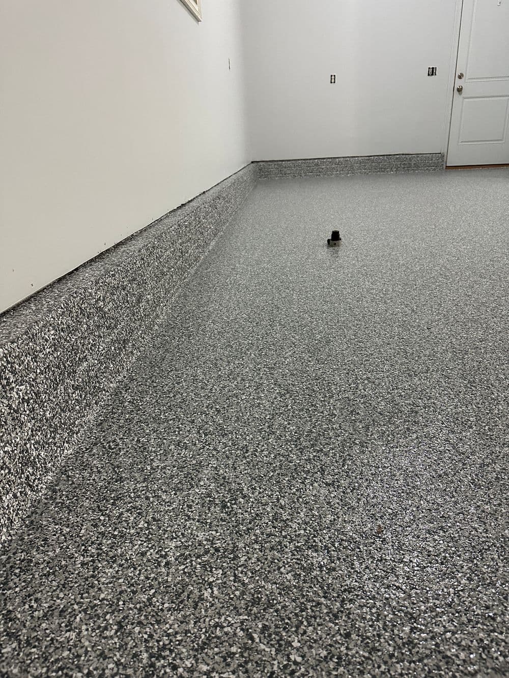 Epoxy-coated gray floor with smooth finish and clean edges in an empty garage space.