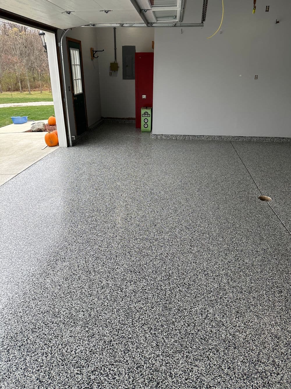 Shiny epoxy garage floor with gray and black speckled finish, clean and well-maintained space.