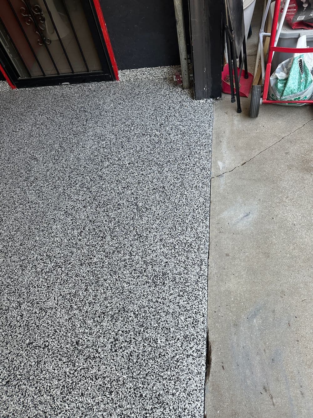 Epoxy flooring in a garage with textured gray and black design, showcasing clean edges.